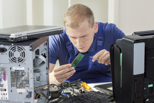 IT Mitarbeiter arbeitet am Mainboard eines PCs IT Mitarbeiter arbeitet am Mainboard eines PCs