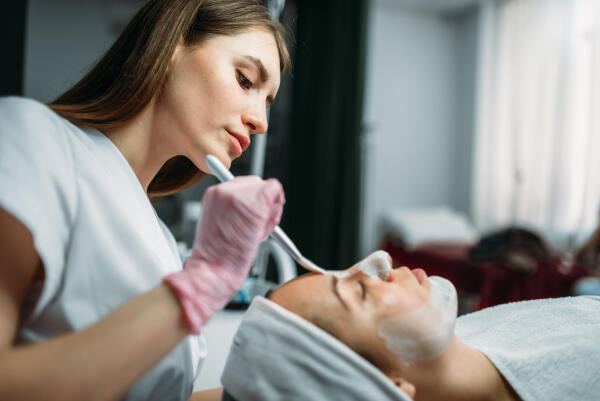 Kosmetikerin trägt Maske auf Kosmetikerin trägt Maske auf